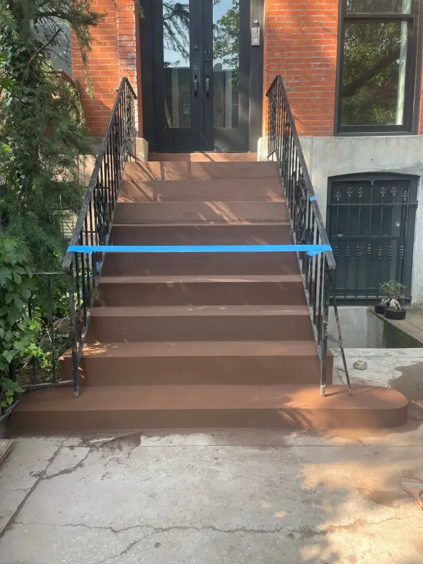 The same stoop after resurfacing — smooth brownstone-toned finish coat, crisp nosings
