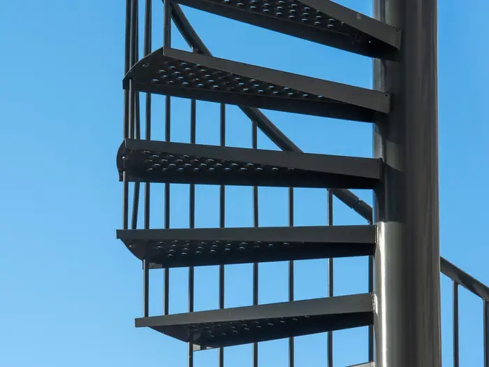 A blackened-steel spiral staircase with perforated treads — the metal in use on stairs (photo: Jan van der Wolf, via Pexels)