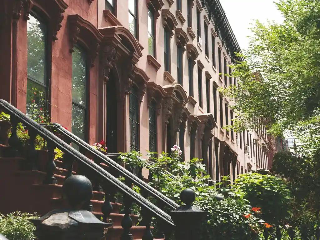 A Brooklyn brownstone facade with carved stone lintels, stoop, and cast-iron railing (brklyn_brwnstne.jpg)