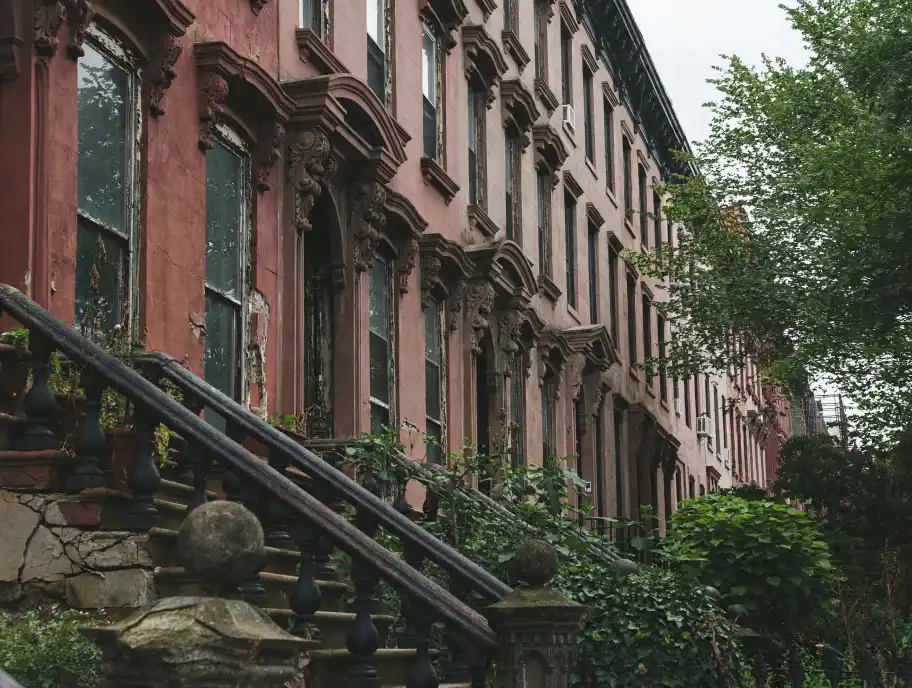 Brooklyn brownstone facade in deteriorated condition — spalling stone, open mortar joints, cracked stoop (illustrated condition study)
