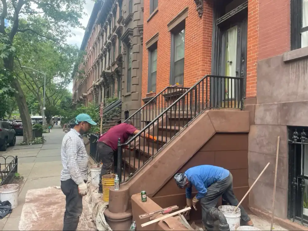 Crew hand-applying the brownstone coating to the stoop at 31 South Oxford Street